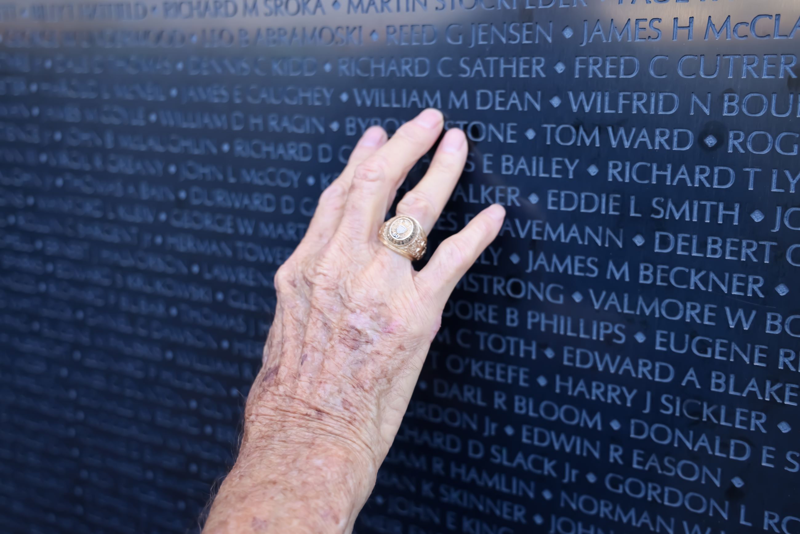 Elderly woman's hand touching The Wall That Heals
